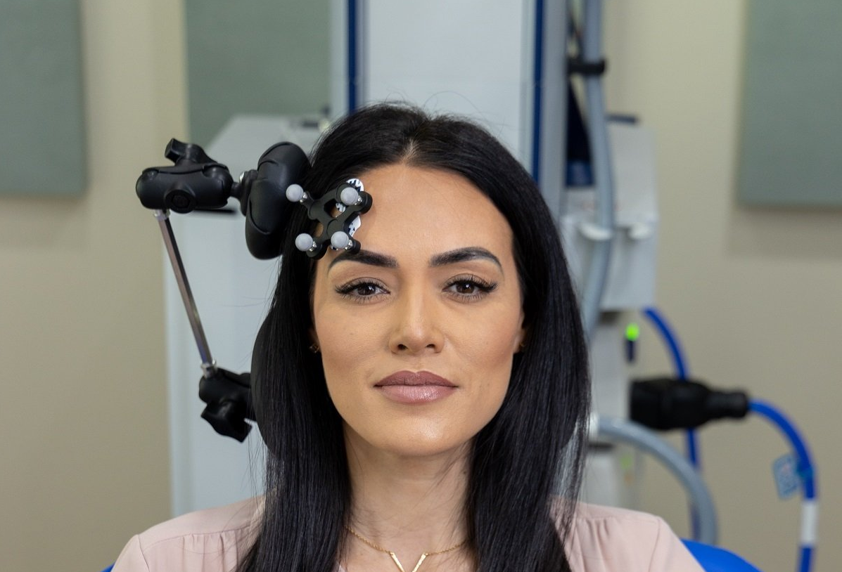 Woman with medical equipment on her forehead, likely undergoing a procedure in a clinic.