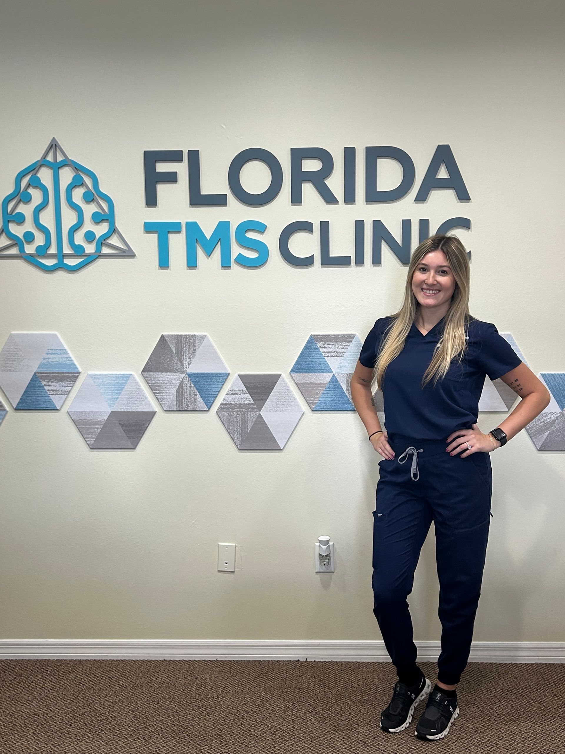 Woman in scrubs stands in front of 