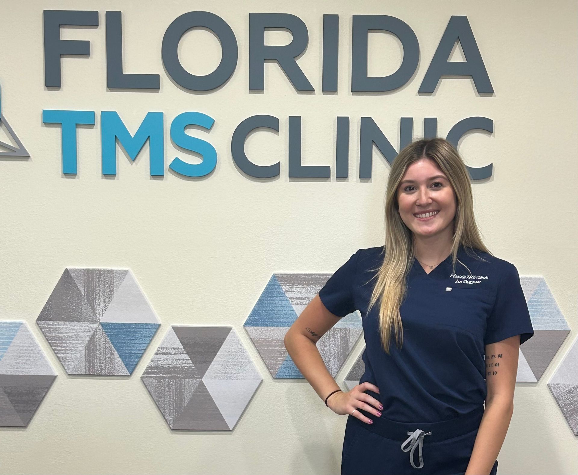 Woman in scrubs smiling in front of 