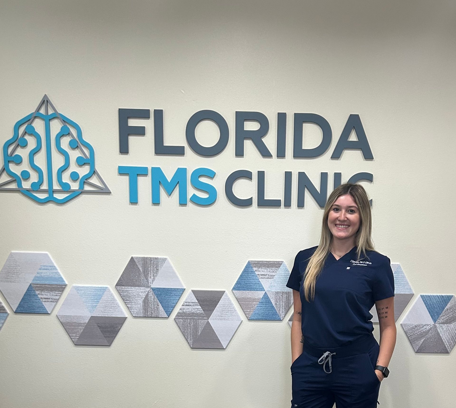 Woman in scrubs stands in front of 