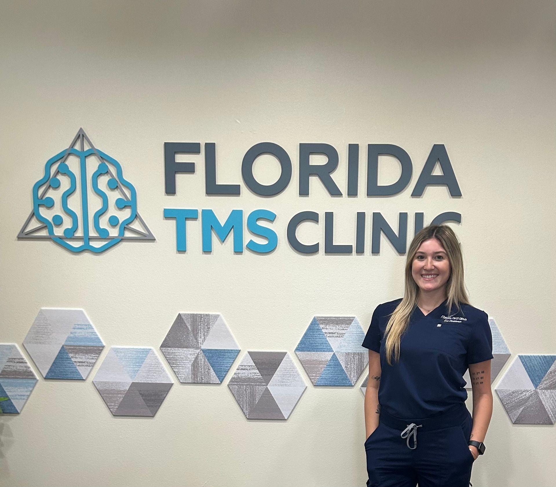 Woman in scrubs smiling in front of 
