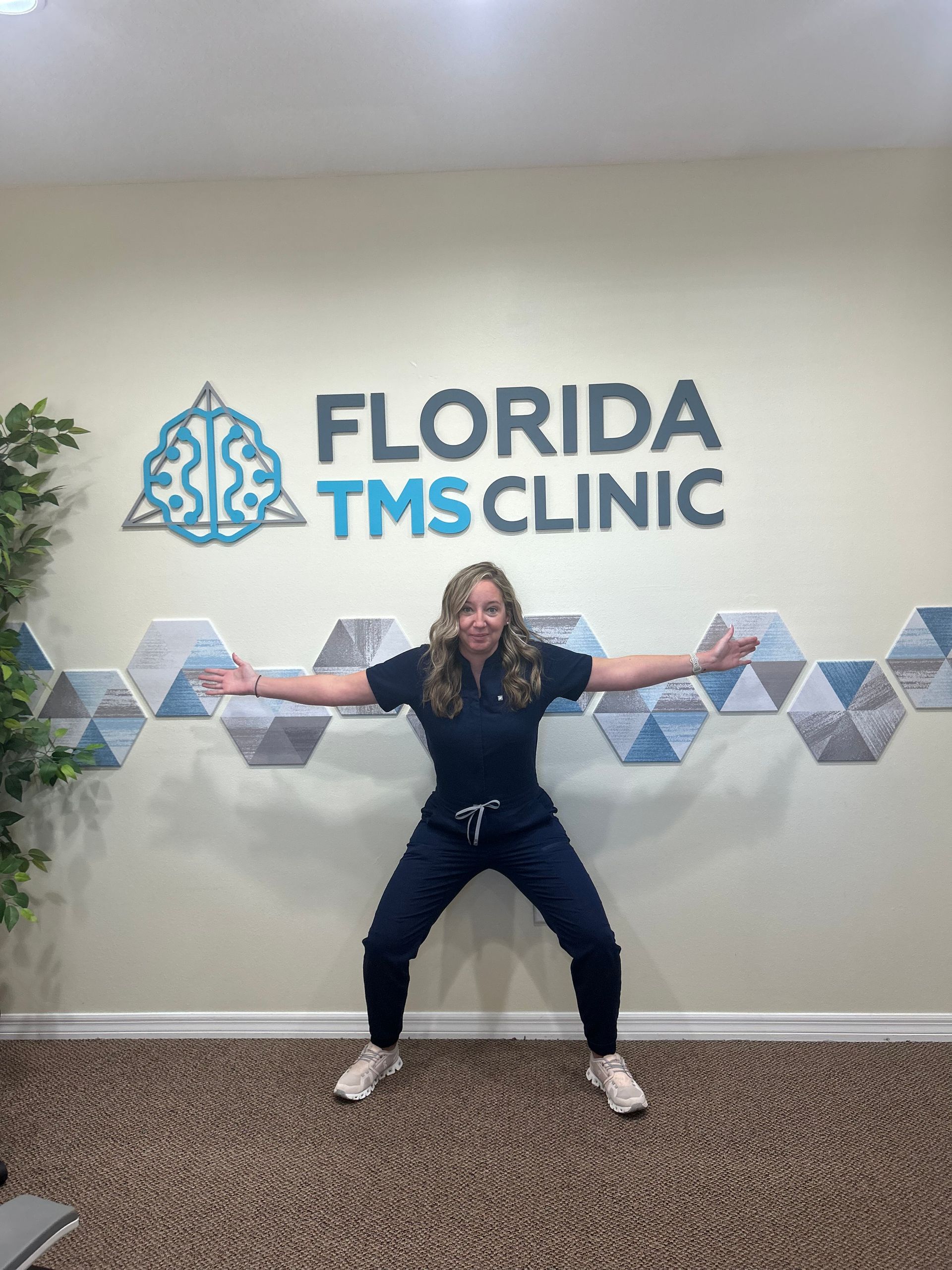 Woman in scrubs, arms out, squatting in front of 
