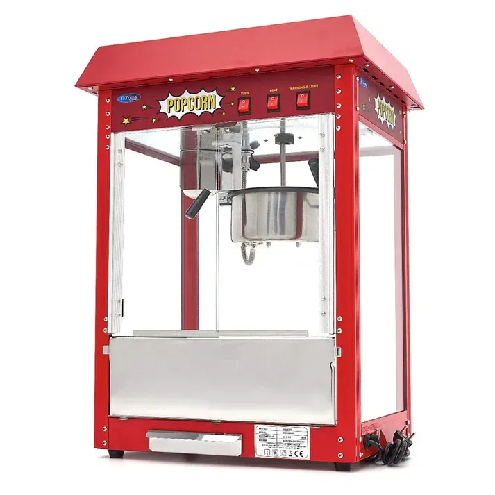 Rode popcornmachine met metalen ketel en glazen panelen op een witte achtergrond.