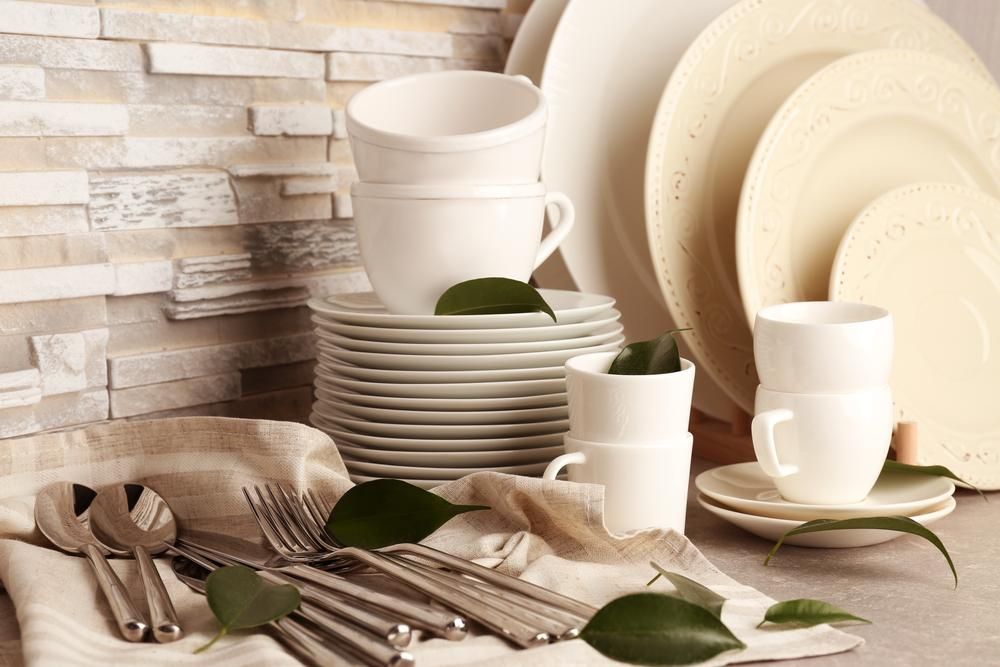 A Stack of White Plates Cups and Silverware on A Table — Mackay Cleaning & Packaging Supplies in Mackay, QLD