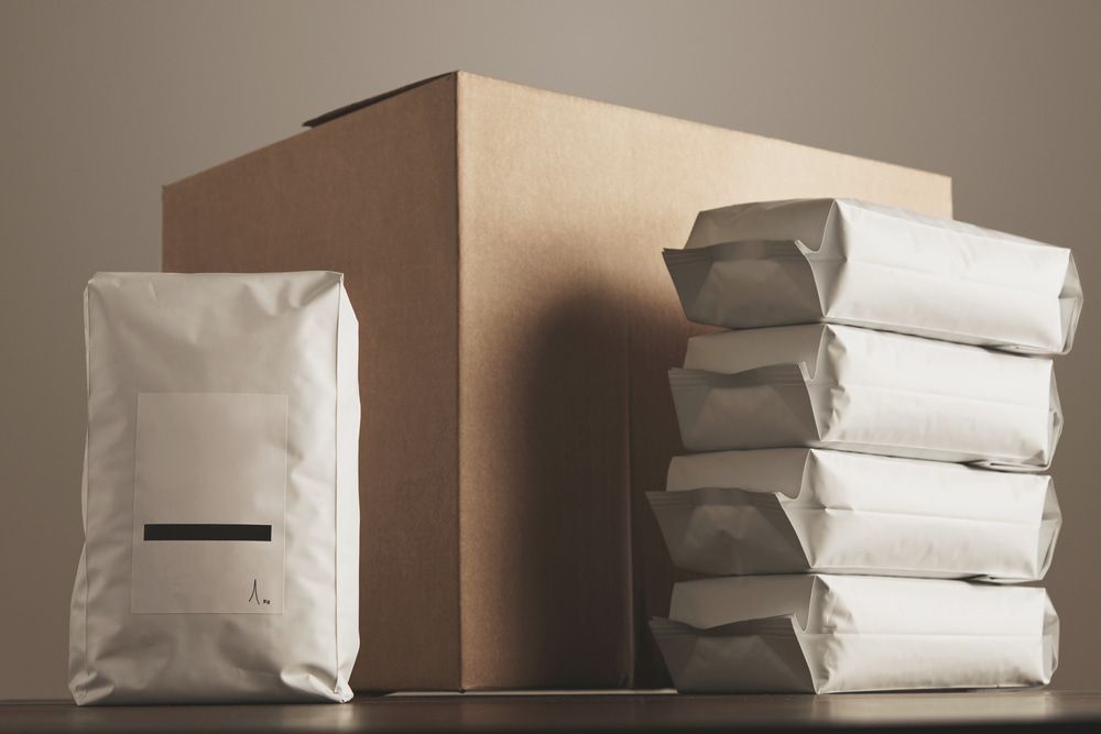 A Cardboard Box and a Stack of Bags on a Table — Mackay Cleaning & Packaging Supplies in Mackay, QLD