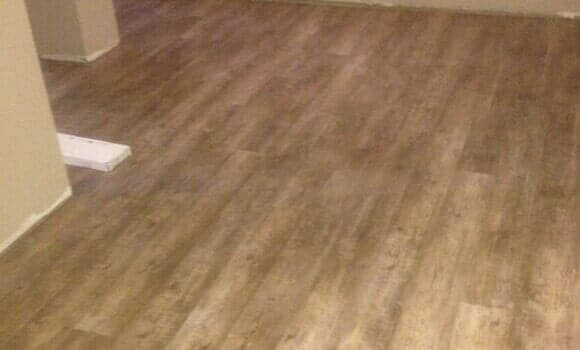 Light brown wood-look vinyl plank flooring covering a room with a plain wall corner.