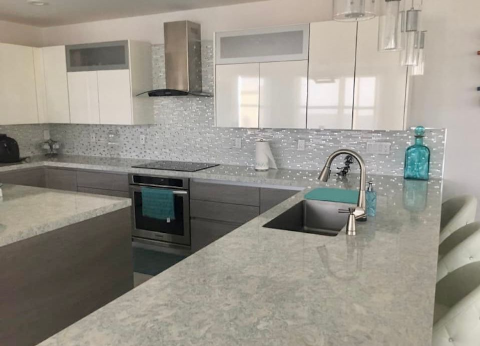 A kitchen with white cabinets , stainless steel appliances , a sink , and a stove.