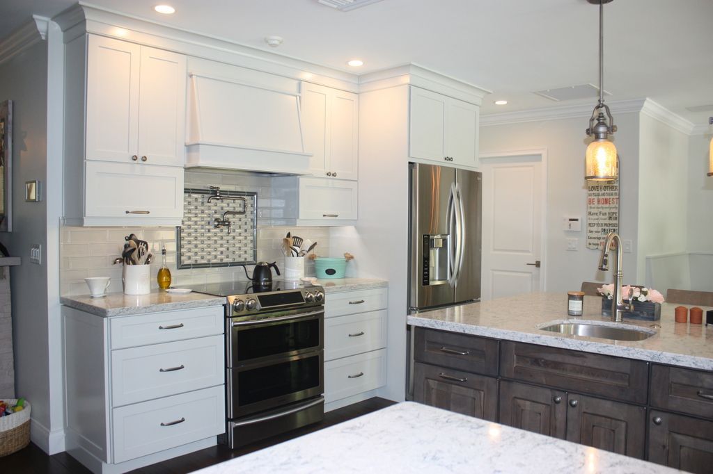 A kitchen with white cabinets , a stove , a refrigerator , a sink , and a large island.