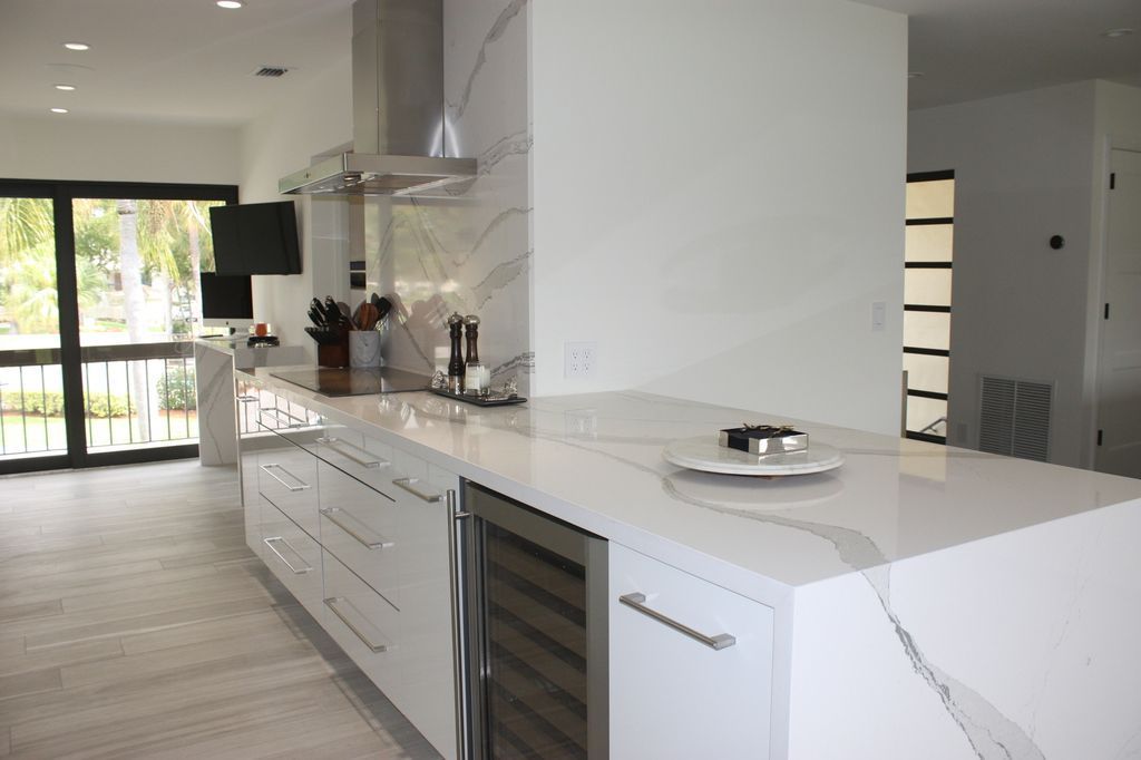 A kitchen with white cabinets and marble counter tops