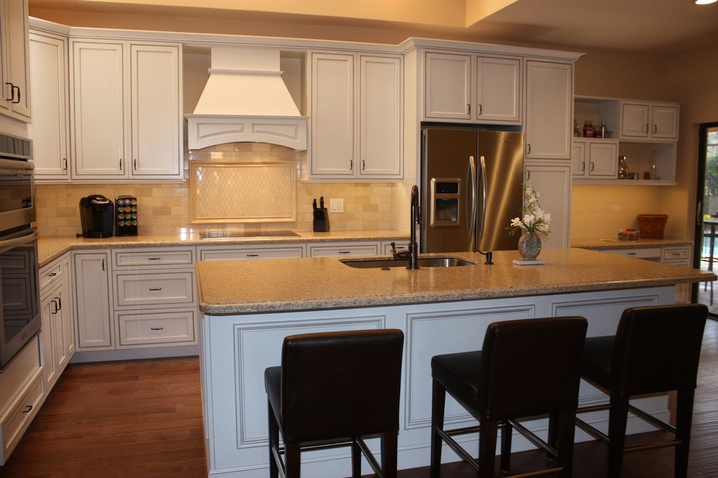 A kitchen with white cabinets , granite counter tops , and a large island.