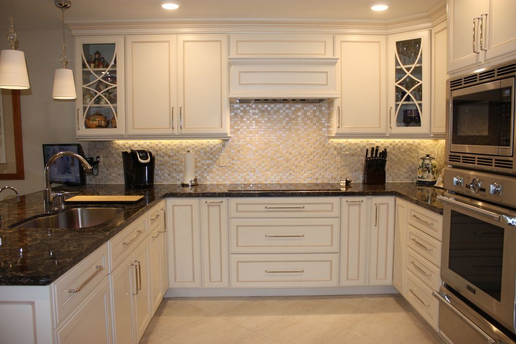 A kitchen with white cabinets , black counter tops , and stainless steel appliances.