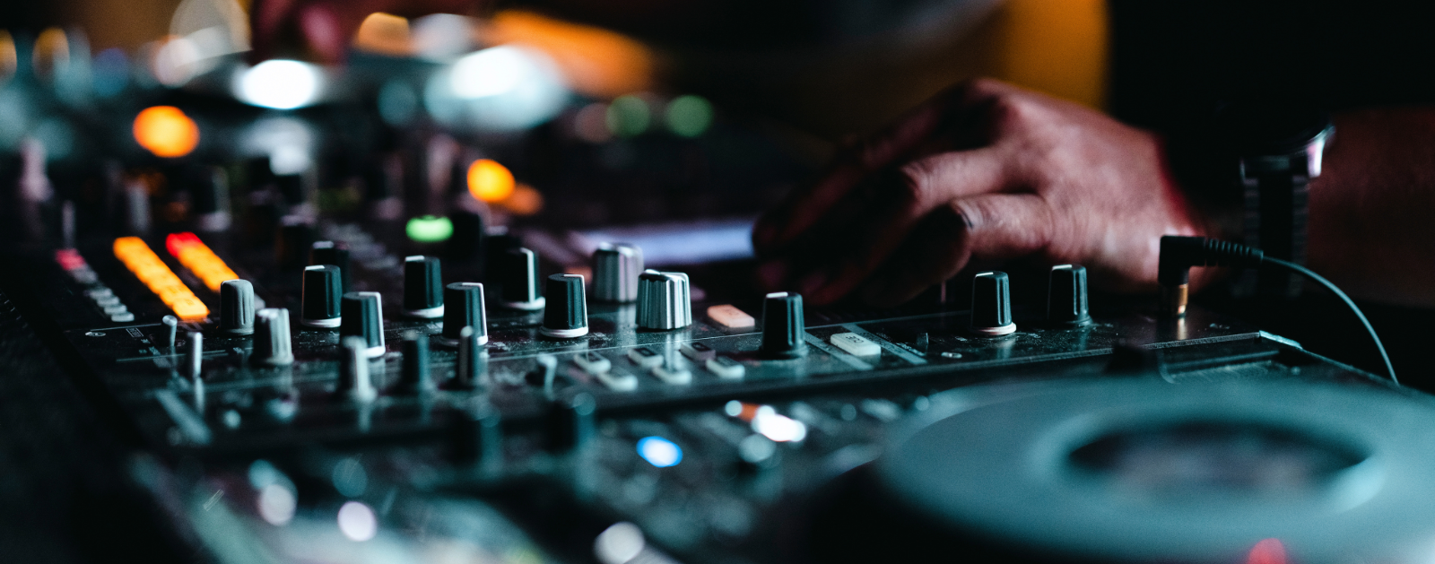 Event DJ adjusting sound levels on turntable and mixer board.