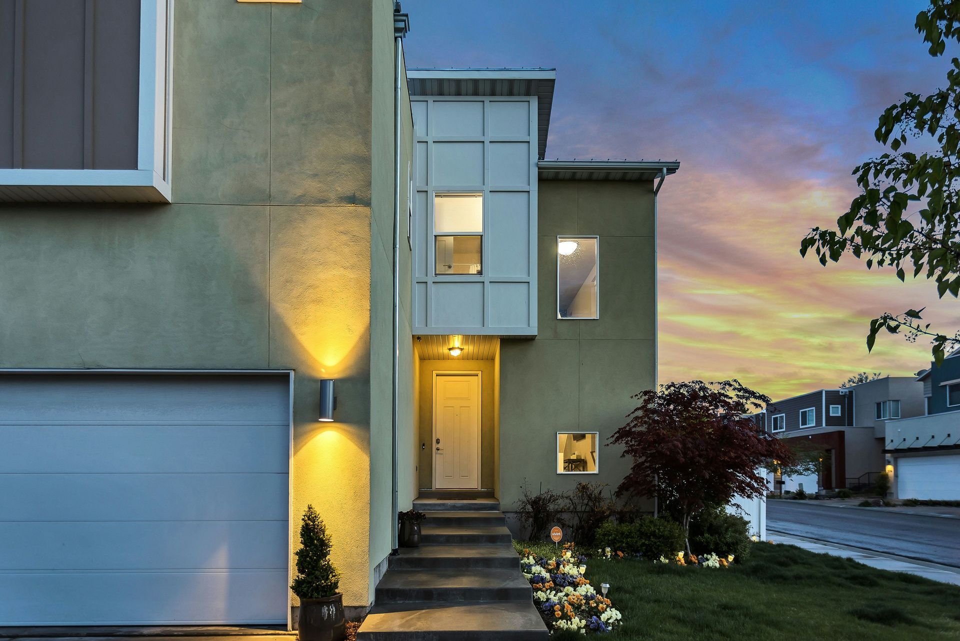 Modern house exterior at dusk with garage and lighted entrance.