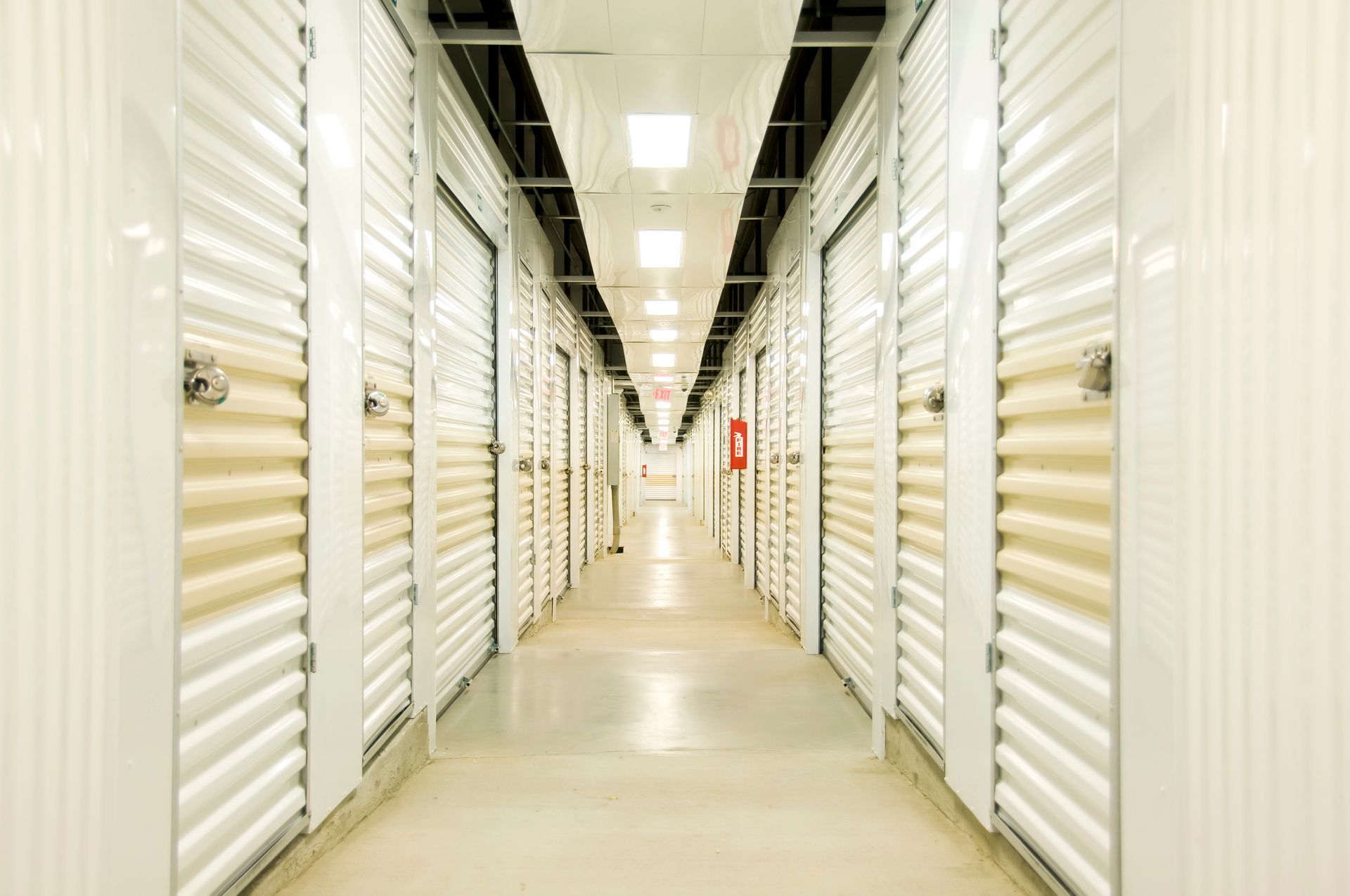 Long, white storage unit hallway with doors on both sides.