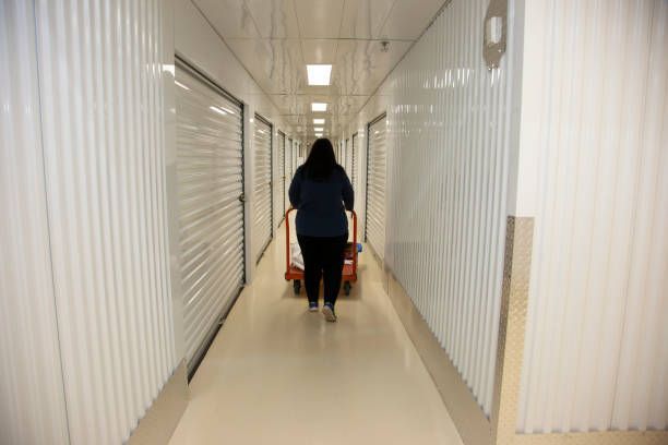 Person with a dolly in a white storage unit hallway.