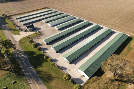 Storage Solutions facility top view — Storage in Terre Haute, IN Aerial view of a storage unit facility with green roofs, concrete pads, and a gravel drive in a rural setting.
