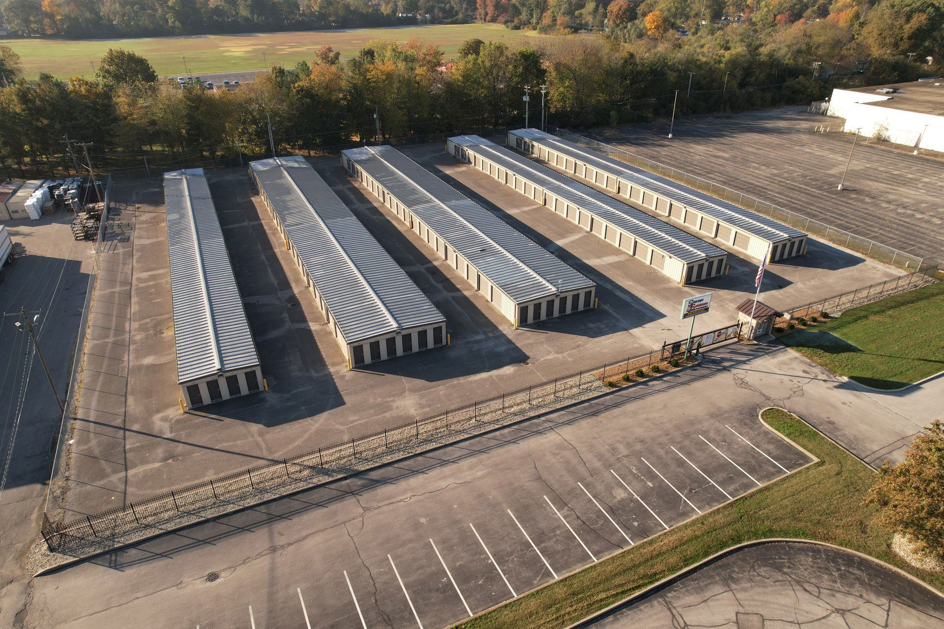 Aerial view of storage units with parking area, surrounded by trees.