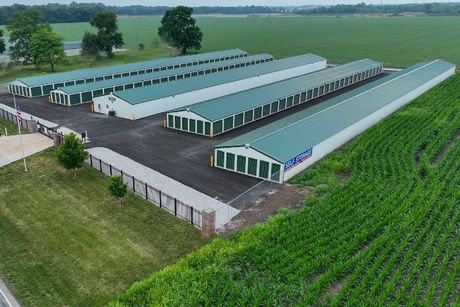 Storage Solutions Annex Storage units with green roofs and white walls, next to a field.