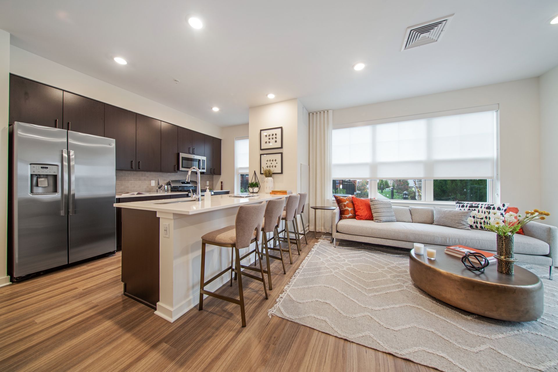 Modern kitchen and living room with stainless steel appliances, breakfast bar, and sofa.