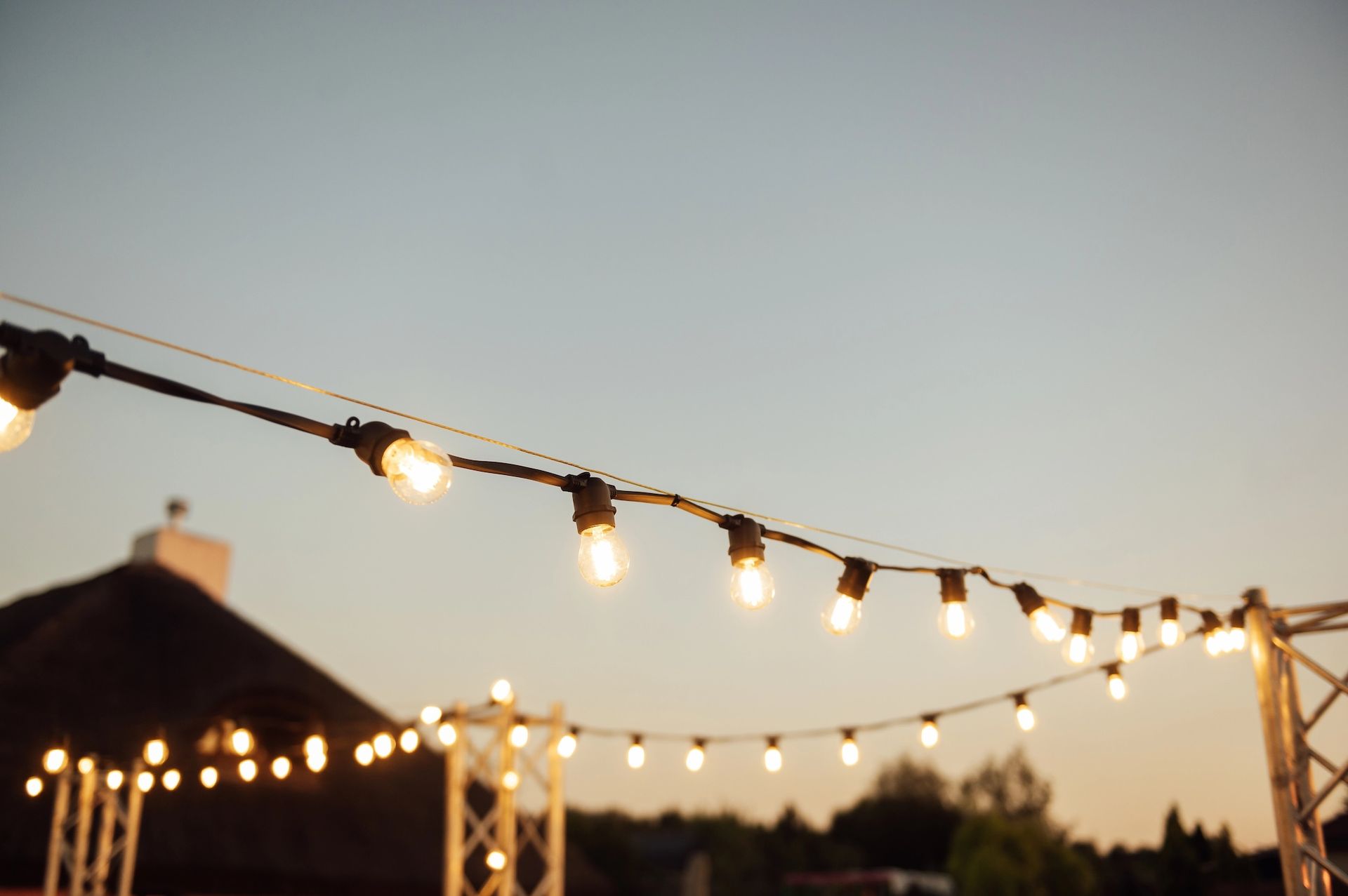 String lights hanging outdoors, against a soft sunset sky.