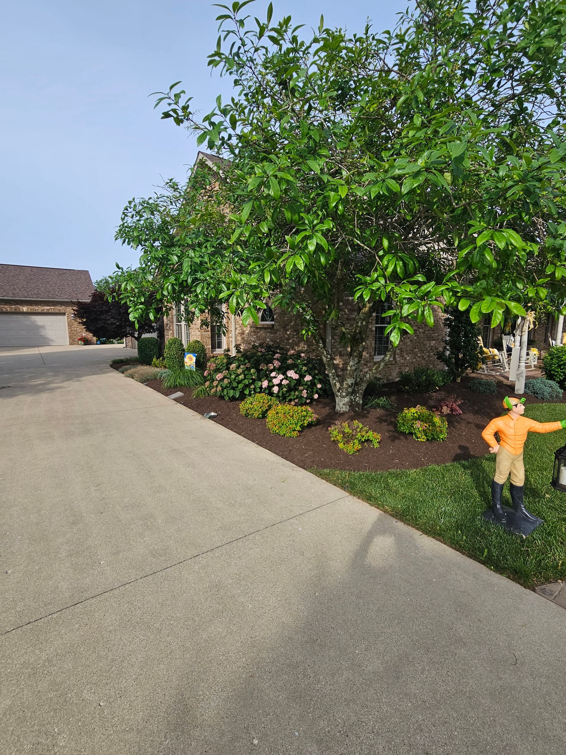 Driveway leading to house with landscaping and a statue of a person.