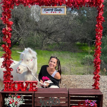 a woman is posing for a picture with a white unicorn .