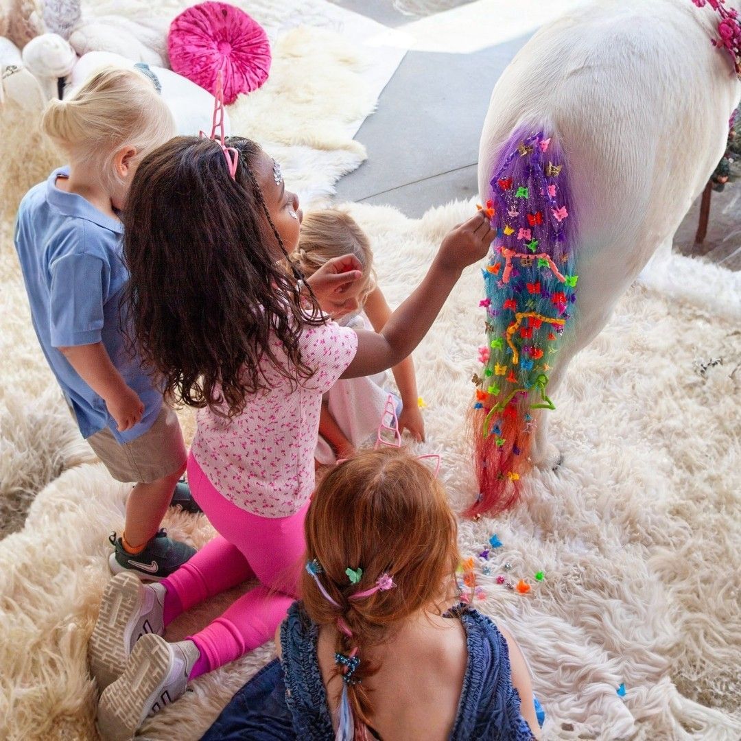 Children petting a white horse while colorful confetti falls on its back