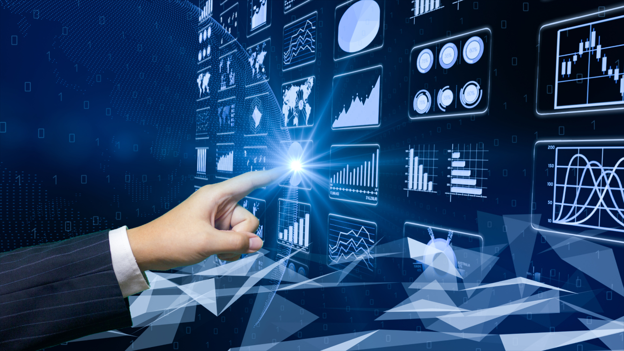 A hand is pointing at a screen with graphs and charts on it.