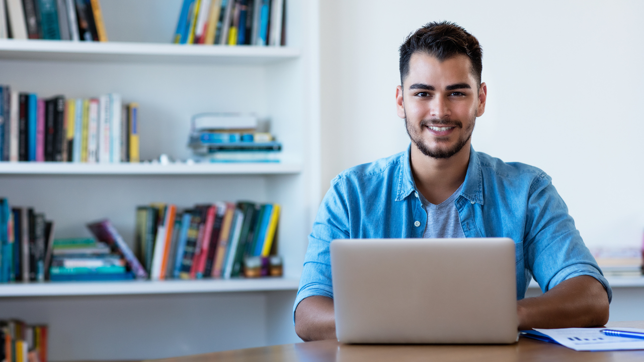 A man is sitting at a desk using a laptop computer.