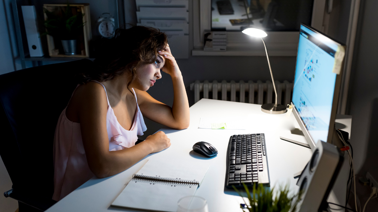 A woman is sitting at a desk looking at a computer screen.