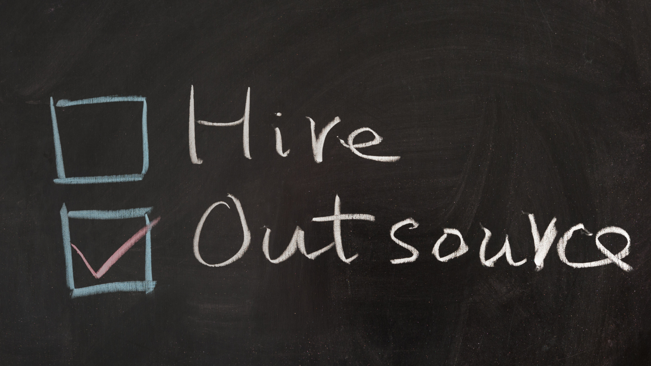 A blackboard with the words hire outsource written on it