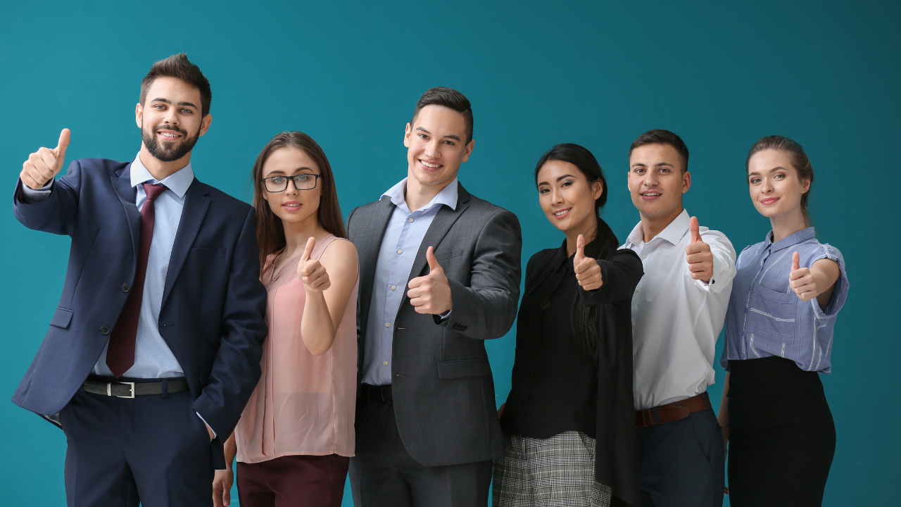 A group of people are standing next to each other and giving a thumbs up.