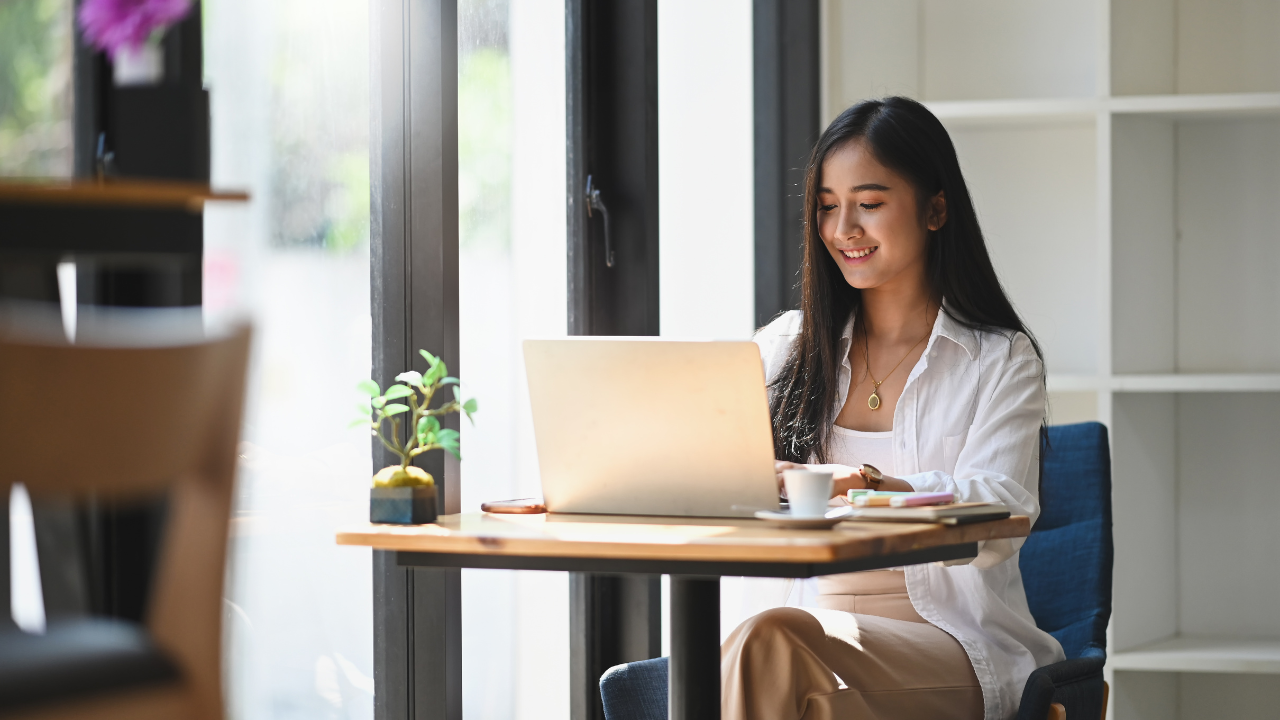 A woman is sitting at a table using a laptop computer.