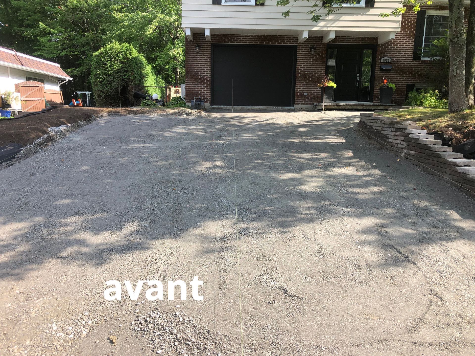 Une allée menant à une maison avec une porte de garage noire.