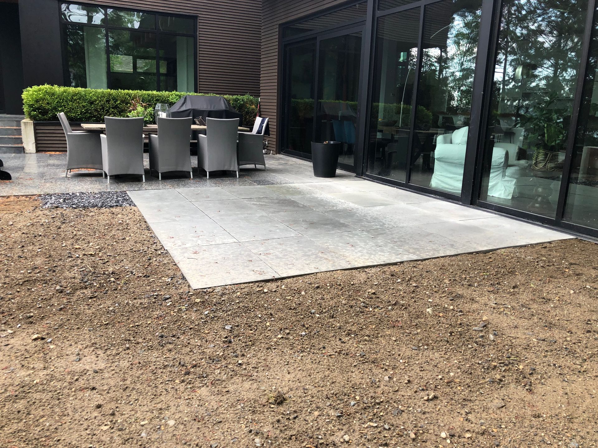 Un patio avec une table et des chaises devant une maison.