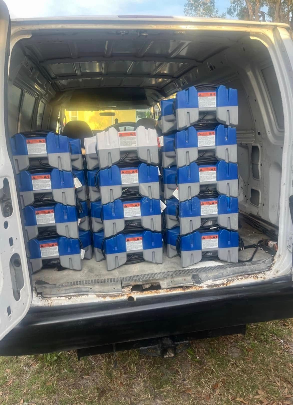 The back of a van filled with stacks of blue and gray containers.