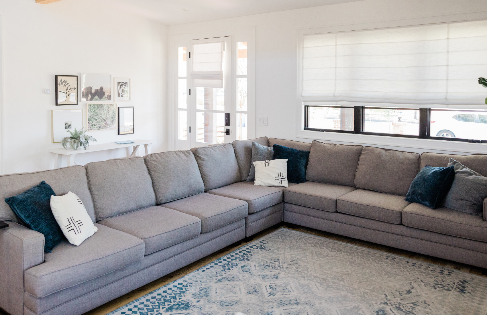 A living room with a large sectional couch and a rug.