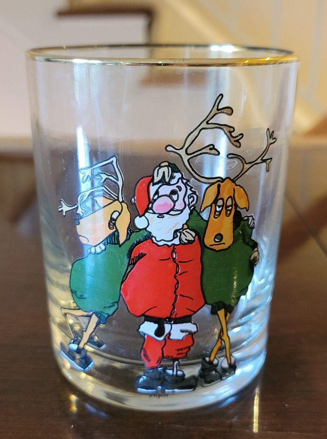 Christmas-themed glass featuring Santa Claus with an elf and reindeer, all in colorful cartoon style.