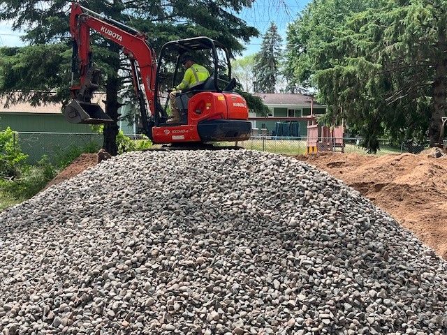 Man is Driving an Excavator on Top of a Pile of Gravel — North Branch, MN — Hassle Free Septic