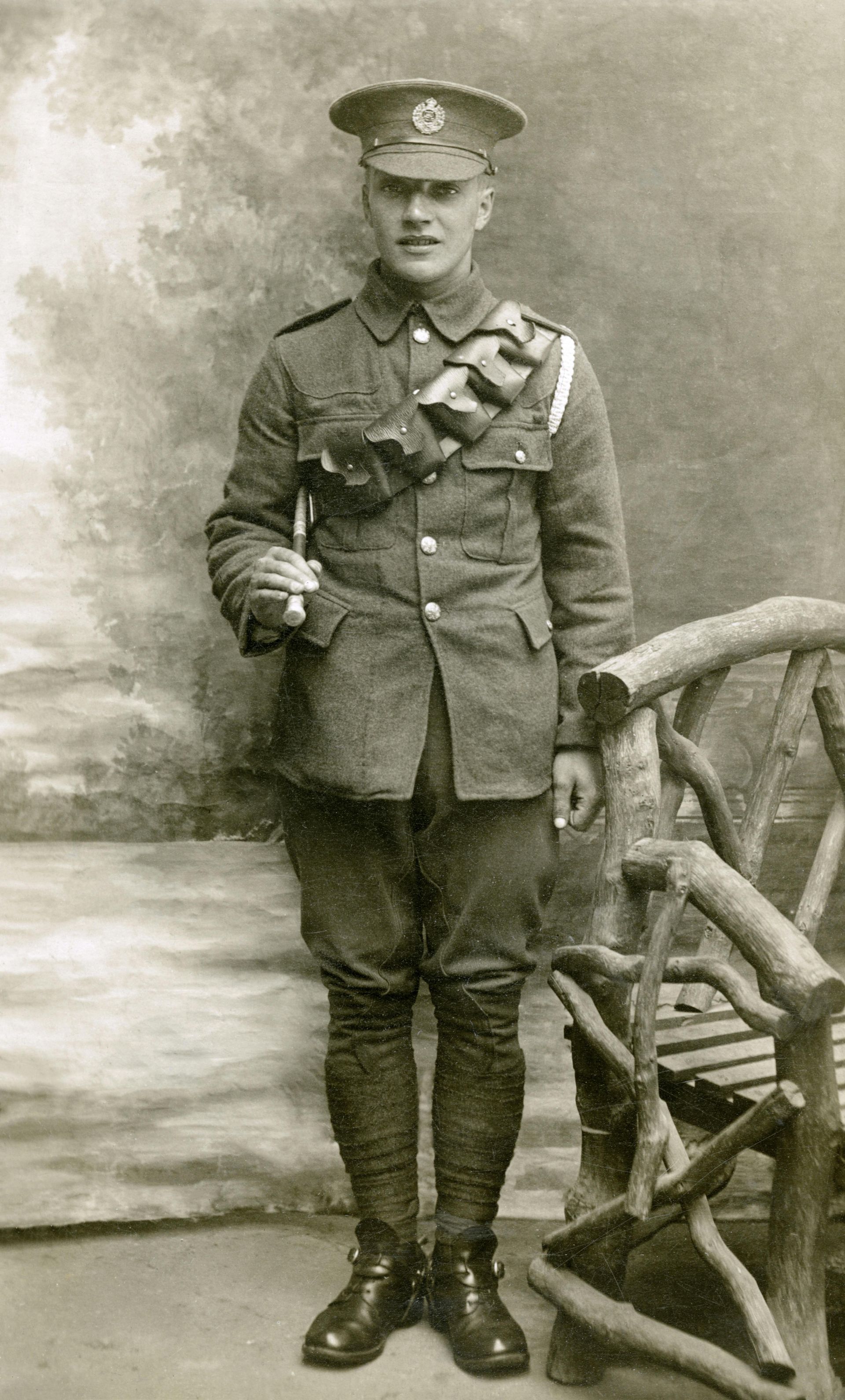 A man in a military uniform is standing next to a wooden chair.