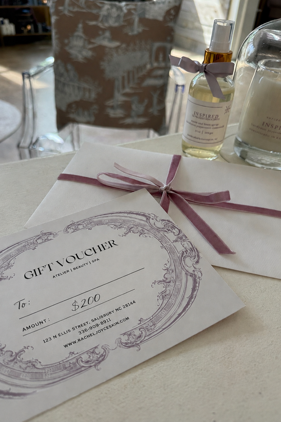 Wedding invitation card tied with pink ribbon on a table, with candles and a decorative gift bag nearby