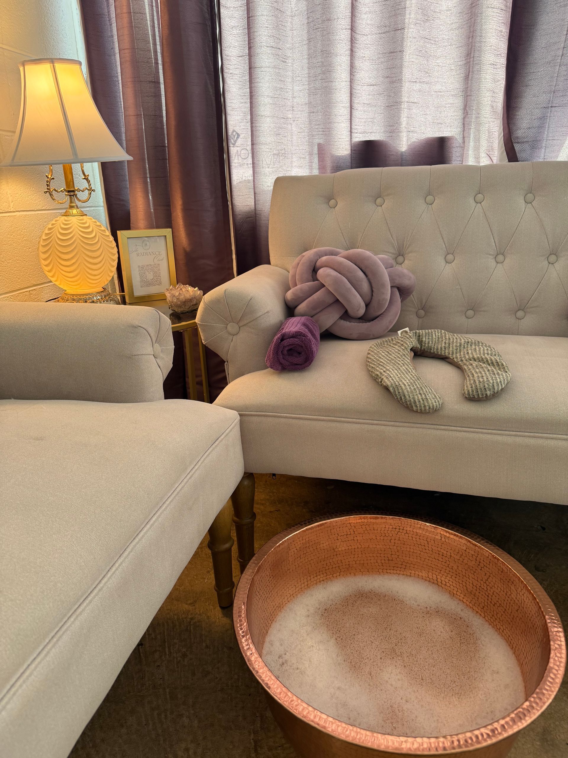 Cozy living room with beige sofas, a floor lamp, throw blankets, and a round pet bed on the floor