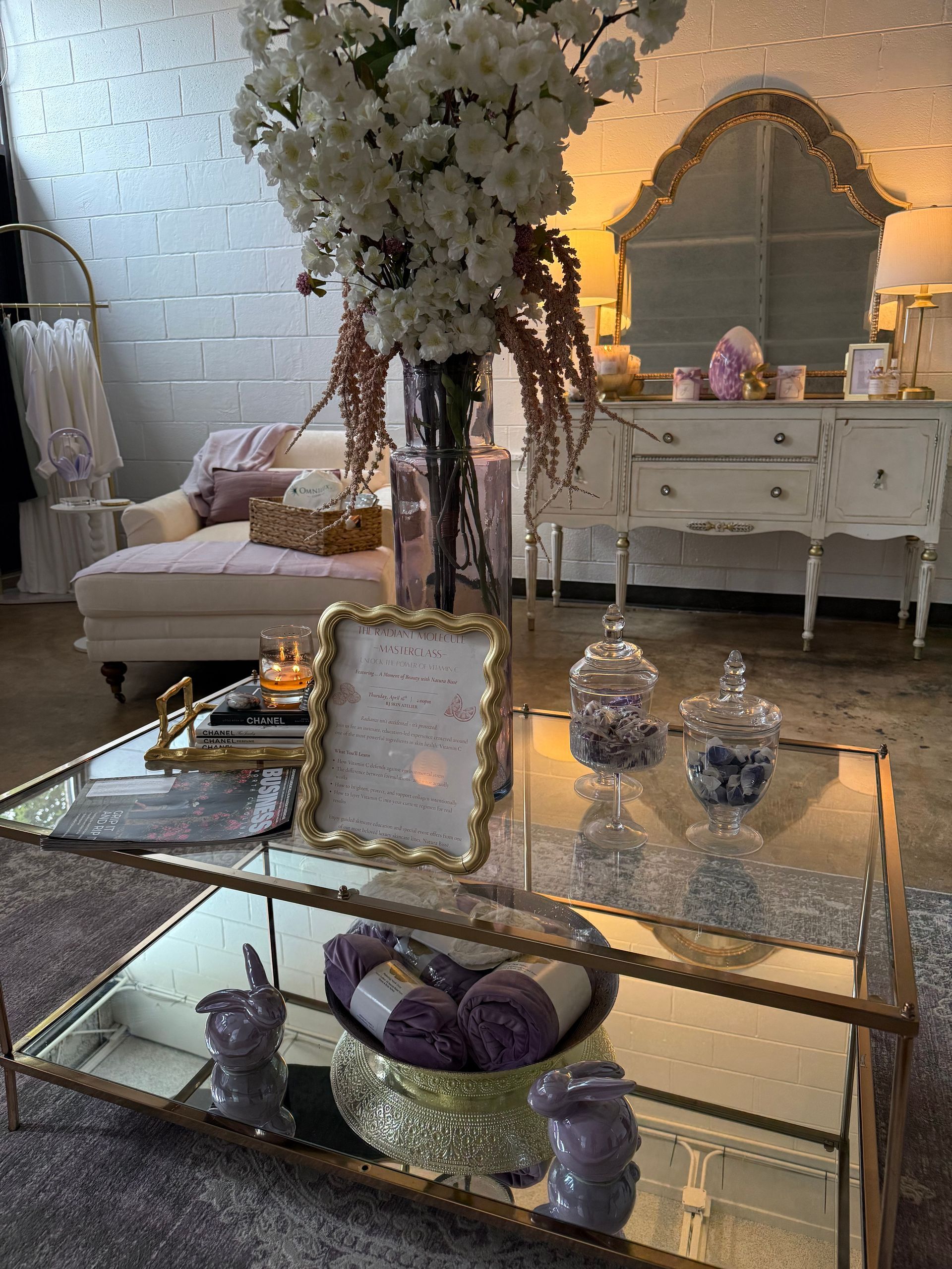 Elegant white living room with glass coffee table, floral arrangements, and ornate decor