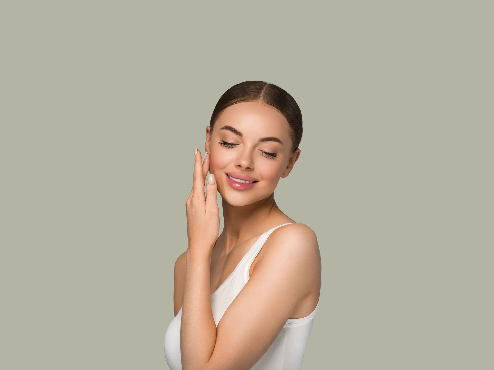 Woman with eyes closed touching her cheek against a plain gray background