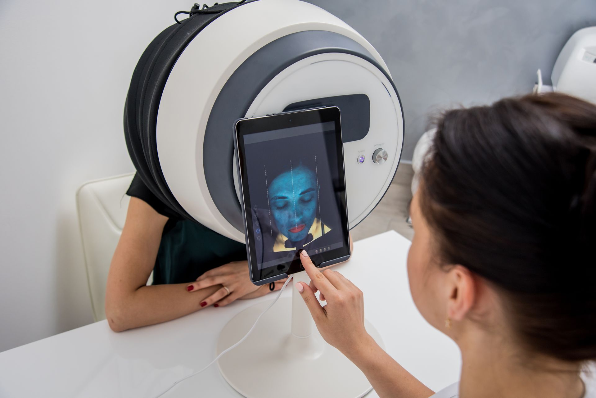 Person holding a tablet with a face scan beside a large circular facial recognition device