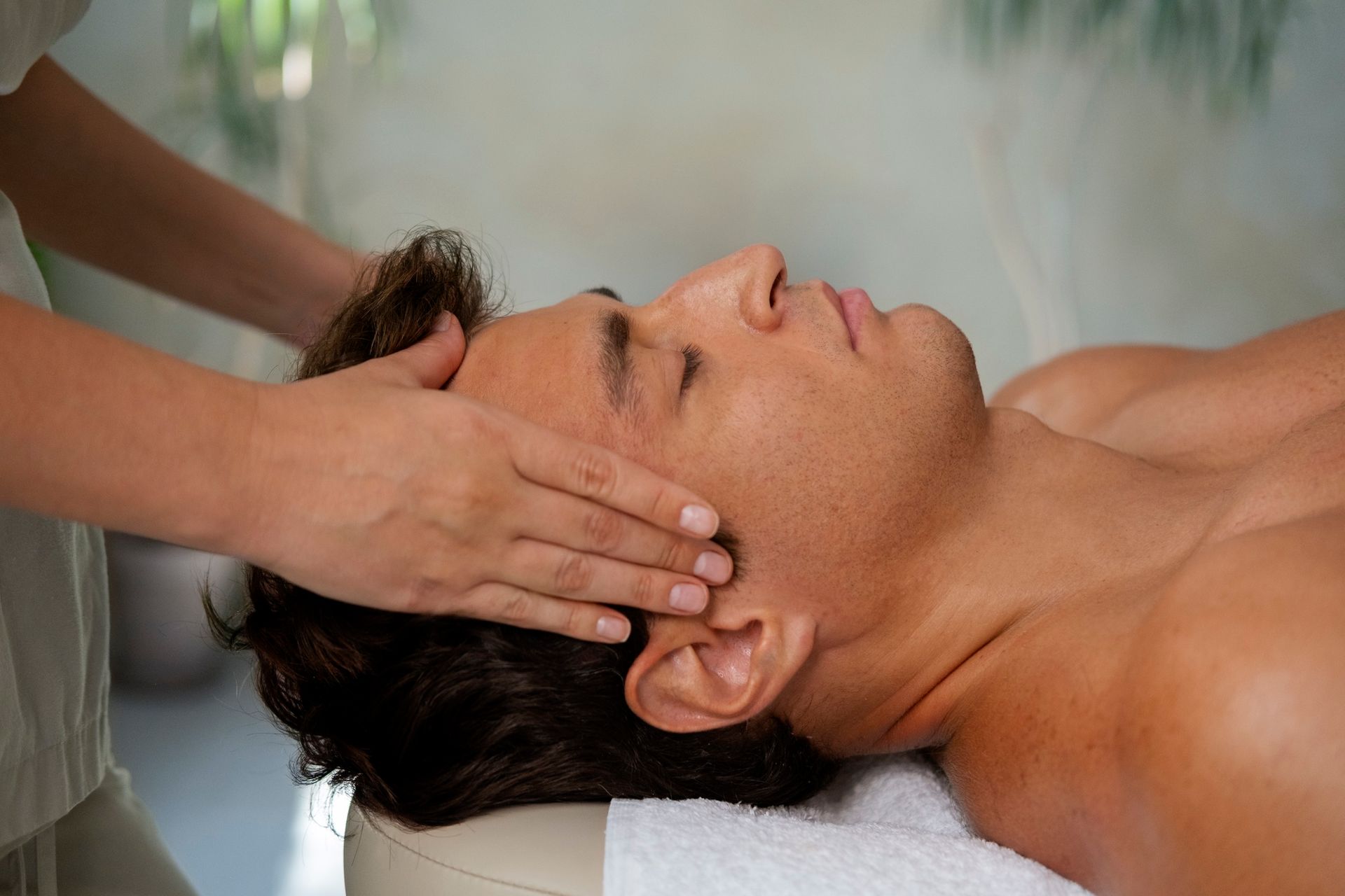 Hands giving a head massage to a reclining person in a spa setting