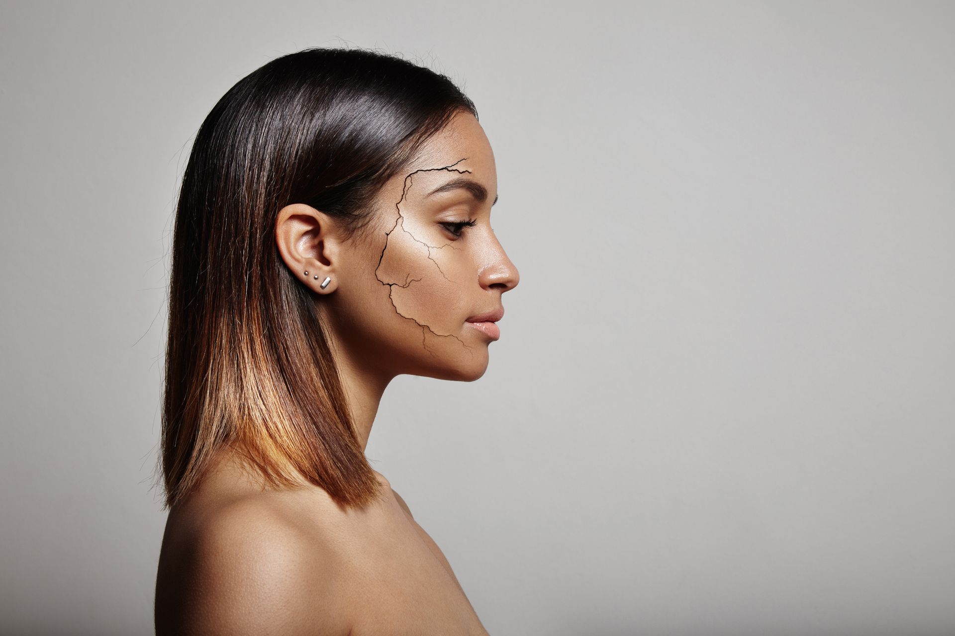 Side profile of a person with visible facial contour lines, looking right against a plain gray background