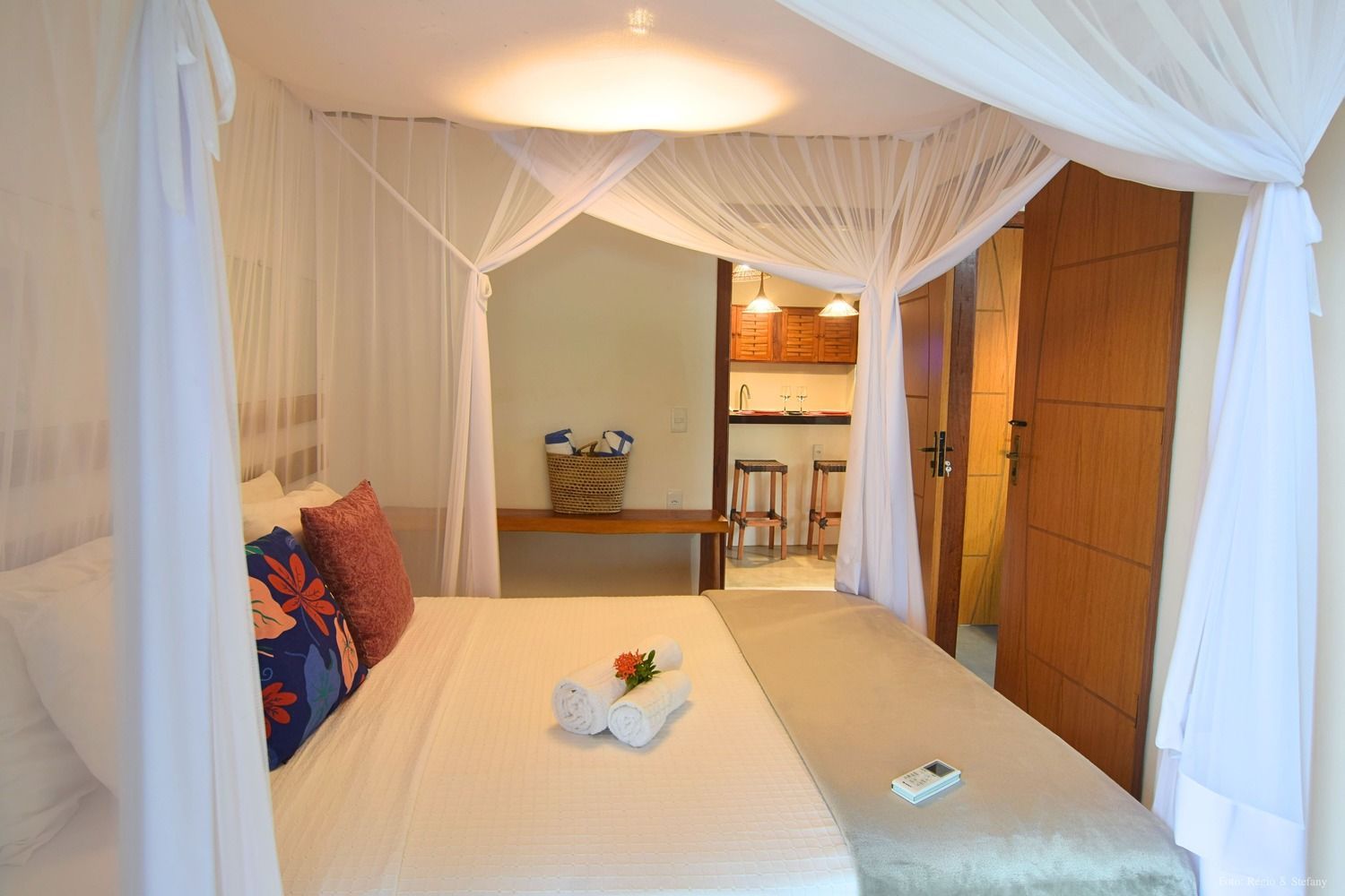 Quarto com cama de dossel, toalhas e vista para a kitchenette.