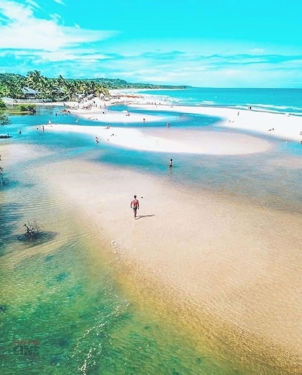 Uma vista aérea de uma praia com um homem caminhando nela. Pousada Quadradinho de Trancoso