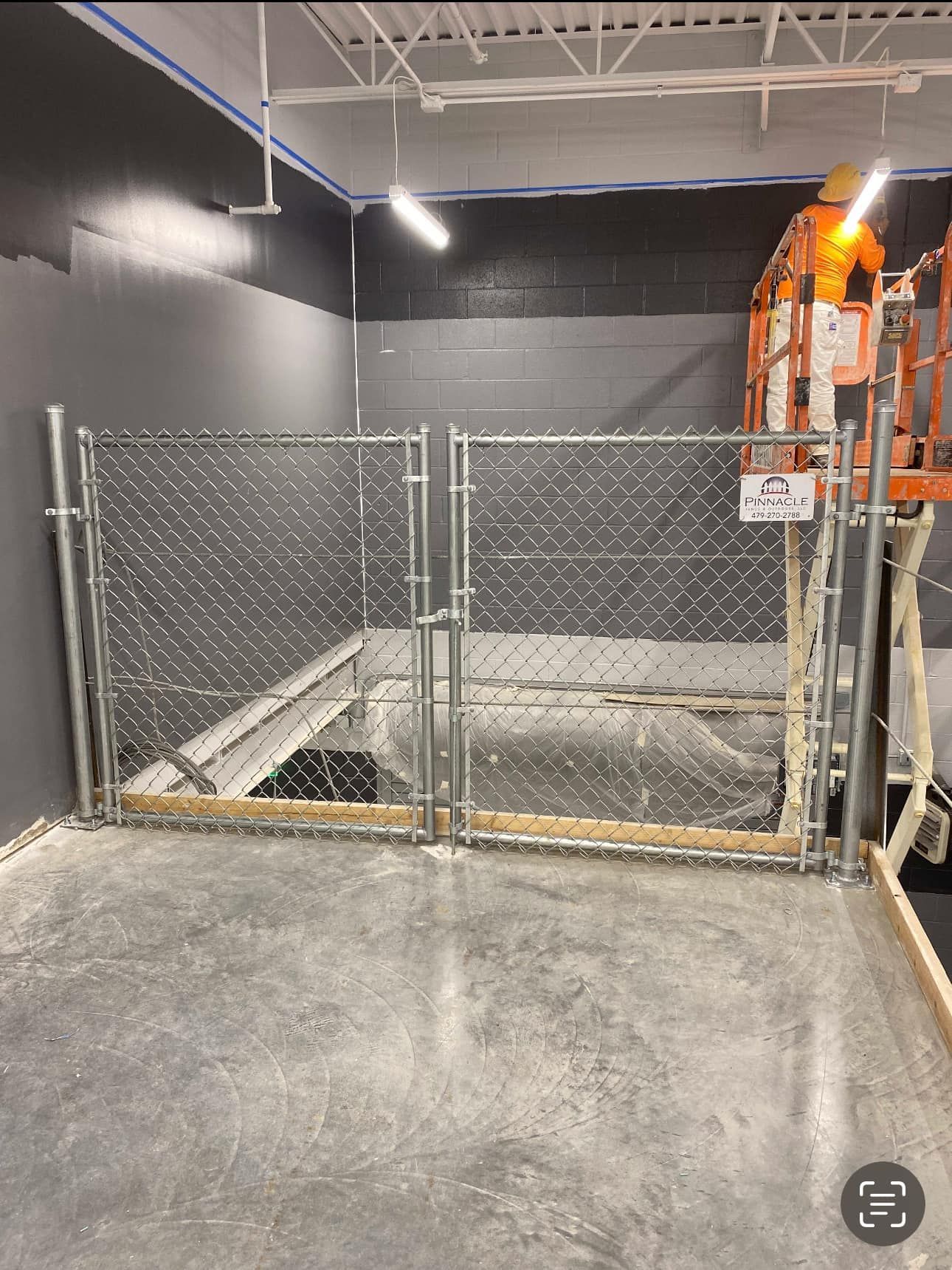 Industrial room with chain-link gate, gray walls, and bright orange equipment on the right